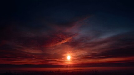Dramatic sunset with fiery clouds and radiant sun over a dark landscape