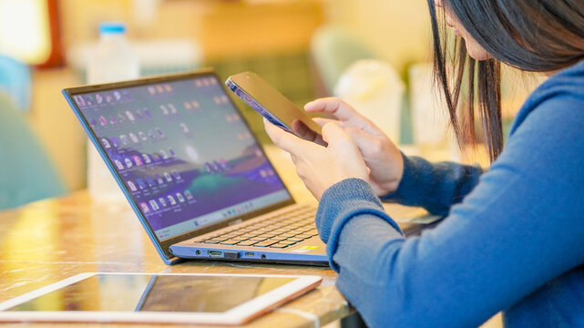 Businesswoman freelance using smartphone and laptop for remote work, project management, browsing internet, AI chatbot or goal planning. Young professionals use phone business startup AI technology