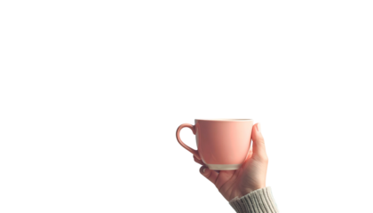 A hand holds a pink mug against a black background. White sweater sleeve visible