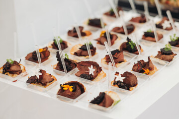 Decorated catering table, banquet with variety of different gourmet exquisite food snacks appetizers on corporate birthday party event or wedding celebration, canape, salad, delicatessen setting