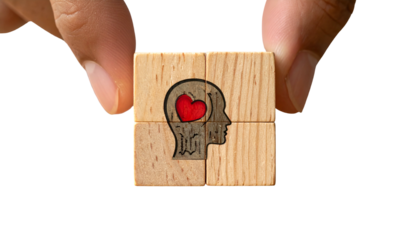 Hand holding wooden puzzle pieces forming a head with heart, set against black