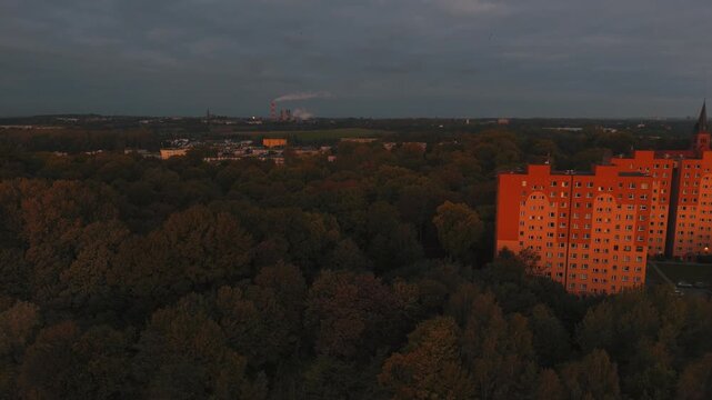 Oddalenie drona odsłania szerszy obszar miasta z parkami i blokami.