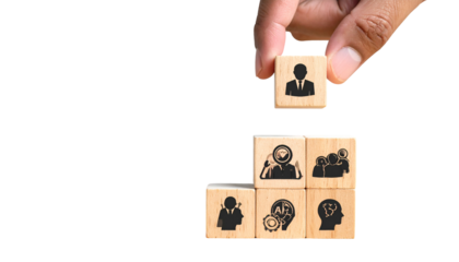 Human hand placing a block with a person icon atop other blocks. Black background
