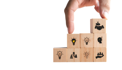 Hand placing a block with handshake icon on a pyramid of blocks with various concept icons