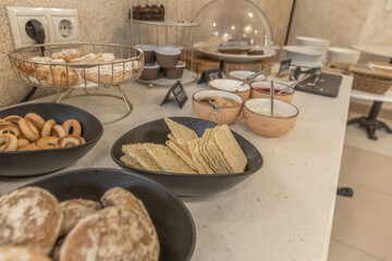 Breakfast buffet with pastries, crackers, cookies, and breads on a clean kitchen counter. Perfect for family gatherings, events, or casual cafe-style snack moments.