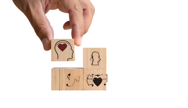 Hand placing a block with a heart within a head on a stack of wooden blocks