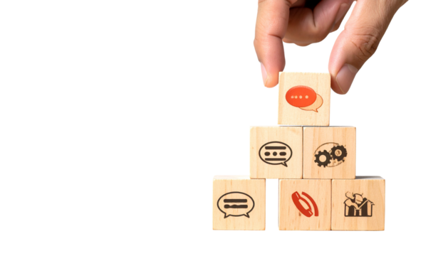Hand placing a communication icon cube atop a pyramid of similar wooden blocks on black