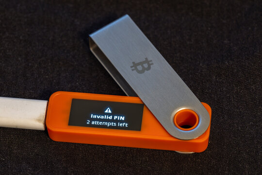 Close-up view of hardware security key displaying an error message indicating invalid PIN with two attempts left. Tense atmosphere captured on dark fabric surface during daytime.