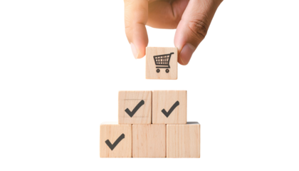 Hand placing a shopping cart cube on a stack of checked boxes, symbolizing completion