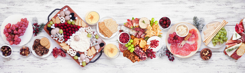 Christmas holiday charcuterie table scene on a white wood banner background. Above view. Assorted...