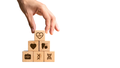 Hand arranging wooden blocks with health symbols into a pyramid against a black background