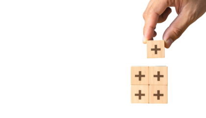 Hand placing a plus block on other blocks with plus signs. Black background