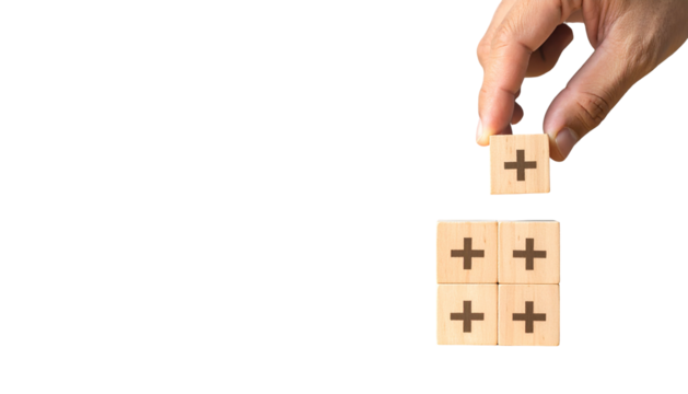 Hand placing a plus block on other blocks with plus signs. Black background