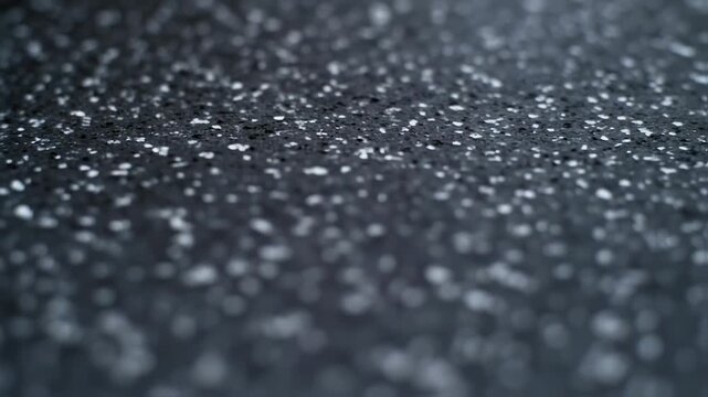 Close up of a dark surface with small white specks, texture detail.