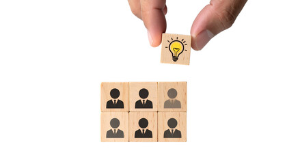 Hand placing a lightbulb icon block above blocks with human figures, symbolizing teamwork