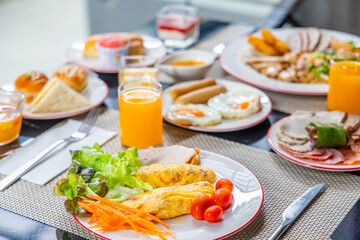 Breakfast spread with omelette, vegetables, fresh juice. Indoor dining setting, vibrant healthy meal, balanced diet concept.