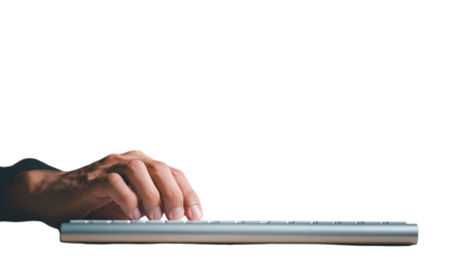 Hand typing on a modern silver keyboard against a dark background, isolated