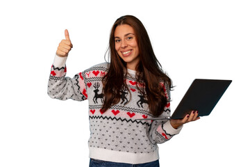 Young woman wearing a christmas sweater and holding a laptop, giving a thumbs up gesture, transparent background