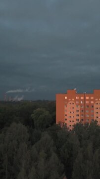 Dron schodzi w d&oacute;ł ujawniając bloki i dym fabryki. Ciemniejsze kolory tworzą klimat industrialny.