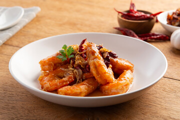 Crispy Prawn in Tamarind Glaze.Pan grilled shrimp topped with tamarind sauce,crispy shallot, and dry chili in white plate.Thai food.