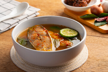 Chak sohm sour curry (gaaeng chak sohm),Thai Sour soup made of Tamarind Paste with striped catfish ,Kaffir Lime and water spinach in white bowl.
