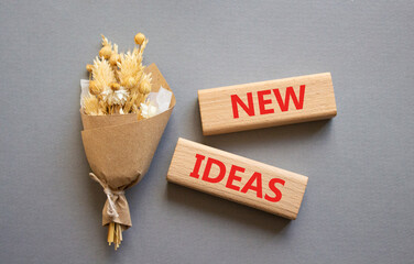 New ideas symbol. Concept word New ideas on wooden blocks. Beautiful grey background with bouquet of flowers. Business and New ideas concept. Copy space
