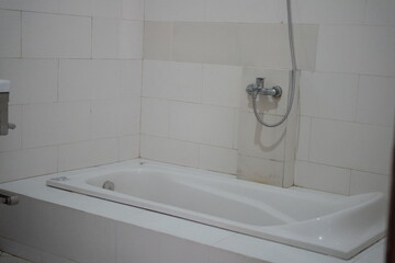 Modern white bathtub with chrome faucet invites relaxation in a clean tile bathroom, perfect for home improvement or hotel design projects