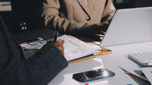 Two businessmen talking in a board room about joint business and summarize the company's profits with a graph showing successful performance. A colleague reviewed the results of the quarterly report.