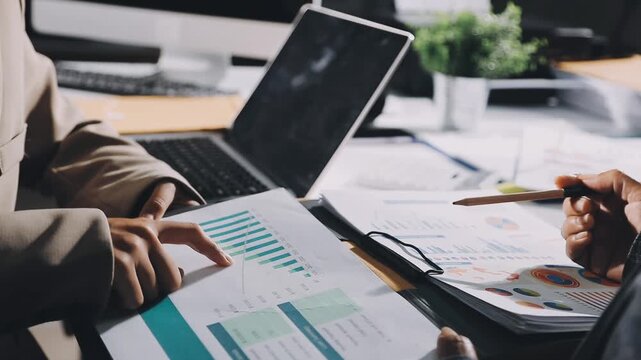 Two businessmen talking in a board room about joint business and summarize the company's profits with a graph showing successful performance. A colleague reviewed the results of the quarterly report.