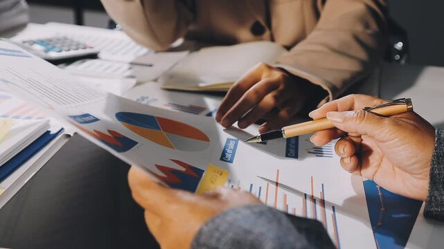 Two businessmen talking in a board room about joint business and summarize the company's profits with a graph showing successful performance. A colleague reviewed the results of the quarterly report.