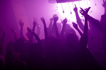 Crowd of friends at a vibrant nightclub event dancing under neon purple lights capturing a festive party atmosphere with music energy
