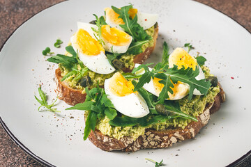 sandwich with mashed avocado, boiled egg, and arugula, on bread , homemade, breakfast,