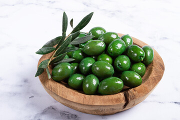 Halkidiki olives, classic Greek green olives, in a wooden bowl, on a marble table, no people,