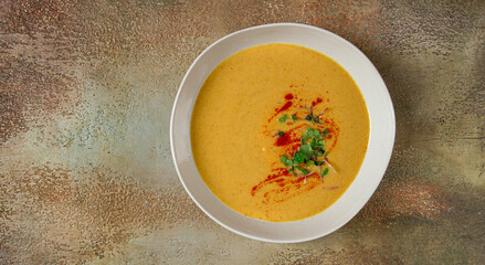 pumpkin cream soup, in a white bowl on a textured background, top view, homemade, no people, rustic style,