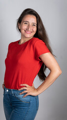 Smiling woman in red shirt posing confidently with hand on hip