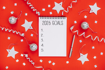 2026 New Year goals background with blank notebook, pen, silver stars and holiday decoration. Space for text. Top view. Christmas to-do list or wish list
