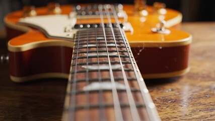 Close up of a hollow body electric guitar showcasing frets strings wood and details on a wooden surface - Powered by Adobe