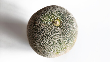 A whole Japanese or Cantaloupe melon shown on a white background, distinguished by its deeply textured, netted rind with a distinct circular indentation at the stem end