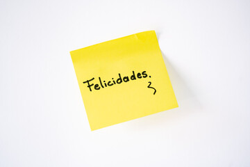 The word &lsquo;congratulations&rsquo; written on a yellow sticky note with a white background.