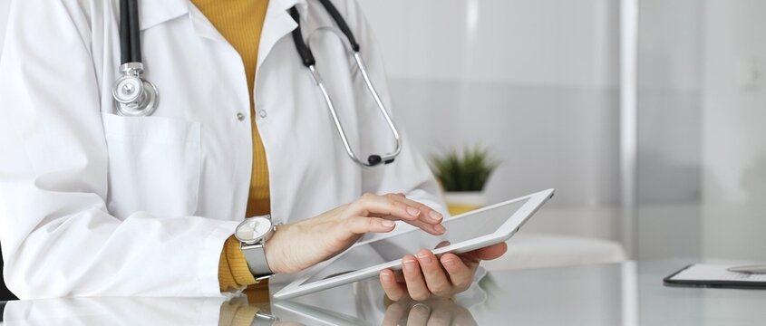 Female doctor using digital tablet, providing modern healthcare and medical technology consultation. Medicine, healthcare and science concept - Powered by Adobe