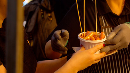 Vendor serving tteokbokki Korean street food to person in night market © 4kclips