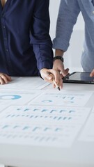 Professional team reviewing financial documents, pointing at charts on desk, collaborating to analyze data and strategize business growth. Business people concept