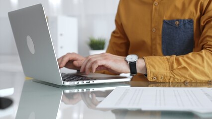 Professional working on laptop, typing at office desk, managing documents and business tasks. Audit and taxes in business