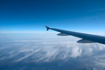 Amazing landscape is visible through airplane window. Traveling by plane. Flying in the sky among clouds.