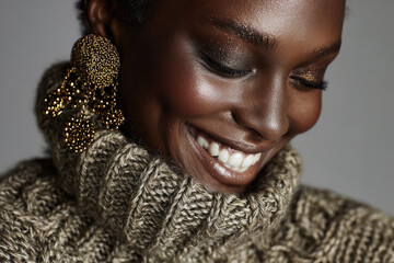 Beautiful smiling black woman in knitted sweater and earrings
