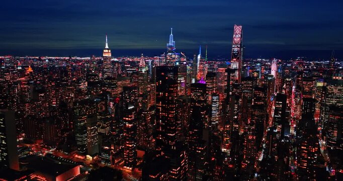 Iconic panorama of New York, USA at night time. Drone footage above the midtown approaching the famous skyscrapers tops.