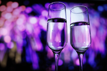 Elegant toast in vibrant ambiance, Intimate revelry with sparkling drinks and colorful lights