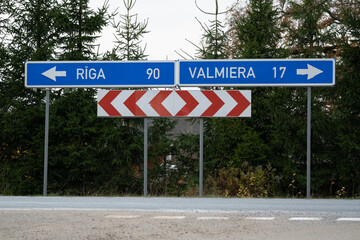 Fototapeta premium Road sign showing directions to Riga and Valmiera in Latvia, concept of travel, navigation, direction choice and decision making on countryside road