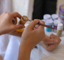 Kid's animator is creating a Shimmering sparkling glitter tattoo on a child's hand at a birthday...