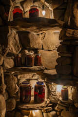 Jars of homemade preserves stand on stone shelves in the basement